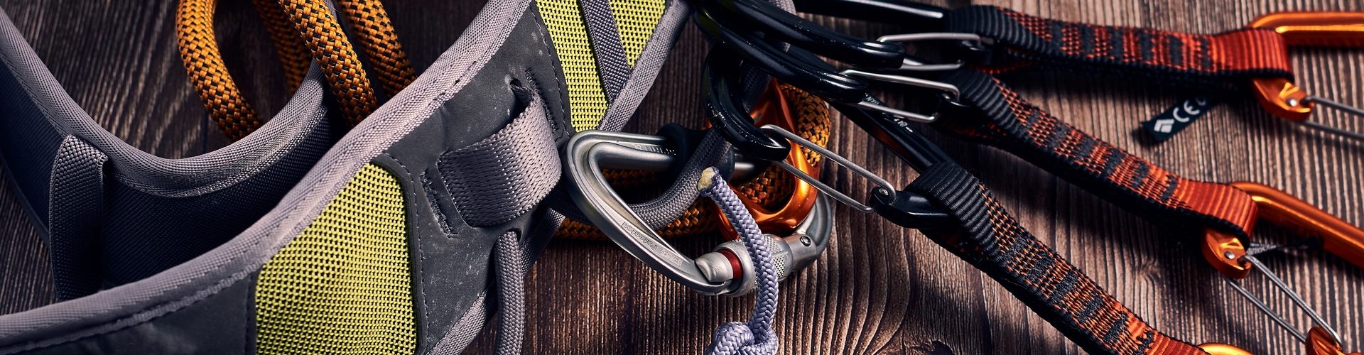 A closeup shot of many colorful climbing carabiners and knots on a wooden surface